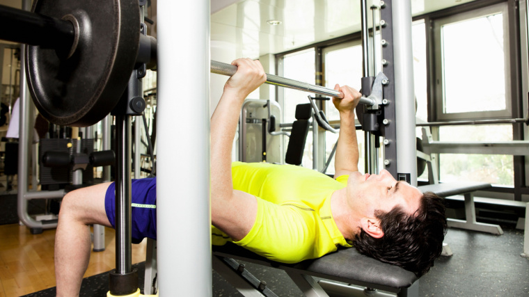 A person bench pressing on a Smith machine in the gym.